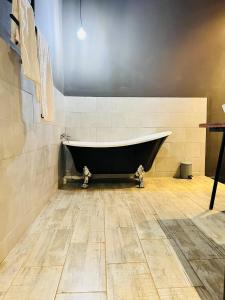 The Shed Venue & Boutique Hotel في ليلونغوي: حوض استحمام في غرفة مع أرضية خشبية