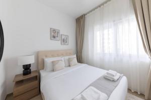 a white bedroom with a large bed and a window at Comfortable 2bd Apartment Next To Metro & Mall in Dubai