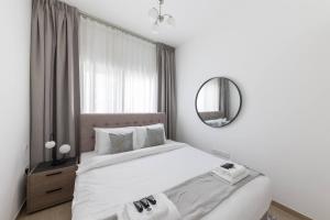 een witte slaapkamer met een bed en een spiegel bij Comfortable 2bd Apartment Next To Metro & Mall in Dubai