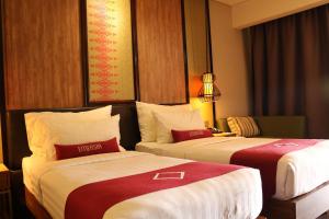 Habitación de hotel con 2 camas con sábanas rojas y blancas en Emersia Hotel & Resort Batusangkar en Batusangkar