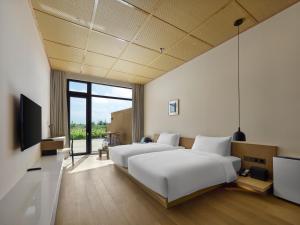 2 lits dans une chambre avec une télévision et une chambre dans l'établissement Jangala Dunhuang, à Dunhuang