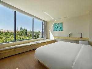 1 dormitorio con 1 cama blanca grande y ventanas grandes en Jangala Dunhuang, en Dunhuang