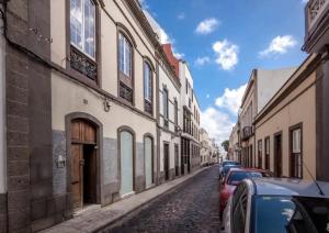 a cobblestone street with buildings and parked cars at Apto Pepita - Casa San Marcial in Triana
