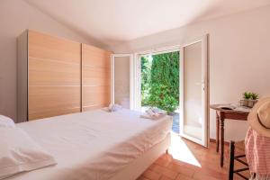 a bedroom with a large white bed and a window at SELECT'SO HOME - Mas des Canadels - Services hôteliers & Prestations de qualité - RCMAS in Rayol-Canadel-sur-Mer