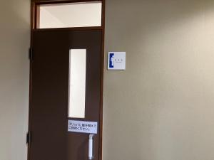 Una puerta con un cartel en una habitación en ビジネスホテルパークイン石巻, en Inai