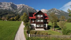 a house in a field with mountains in the background at Appartements Wieseneck - beste Lage inklusive Sommercard in Ramsau am Dachstein