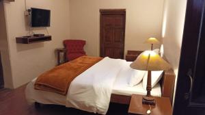 a bedroom with a bed with a lamp and a chair at Tansy Cottage in Dalhousie