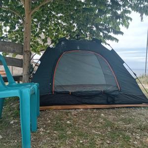 namiot siedzący pod drzewem obok krzesła w obiekcie Thornton's Sea View Cafe & Guesthouse w mieście Siquijor