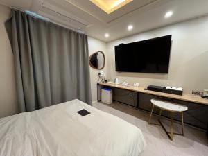a hotel room with a bed and a flat screen tv at Carlton Hotel Bupyeong in Incheon