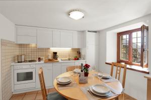 una cocina con mesa y sillas y una cocina con armarios blancos. en Rustico Esterina - Happy Rentals, en Lavertezzo