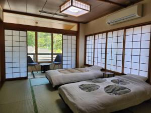 two beds in a room with windows at 大和屋ホテルいろは in Nikko