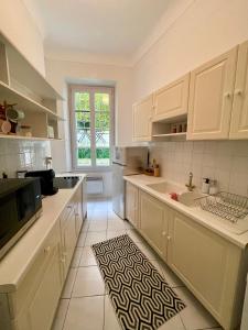 a kitchen with white cabinets and a sink and a window at Frontière Monaco, 2 pièces, centre Beausoleil in Beausoleil