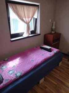 um quarto com uma cama rosa e uma janela em Chergata Guest House em Zheglitsa