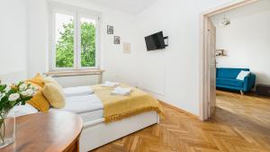 a white bedroom with a bed and a table at Apartamenty Sun & Snow Basztowa in Krakow