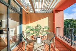 a balcony with two chairs and a plant on it at Two Adjacent King Suites with a Breezy Balcony in Darwin