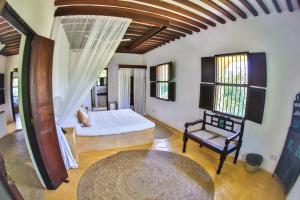 sypialnia z łóżkiem i krzesłem w pokoju w obiekcie Pepo Villa, Anasa Hotels & Experiences w mieście Lamu