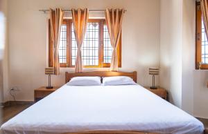 una camera da letto con un grande letto con due finestre di Sundew-n-Lake a Nainital
