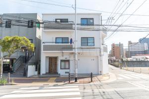 een wit gebouw op de hoek van een straat bij Suite Room PayPayヤフオクドーム Darinホークス通り2F in Fukuoka