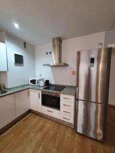 cocina con nevera de acero inoxidable y suelo de madera en Modern apartment a few minutes to the center - TriP, en Málaga