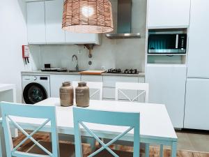 une cuisine avec une table blanche et des chaises bleues dans l'établissement Condominio Serra Dani, à Nazaré