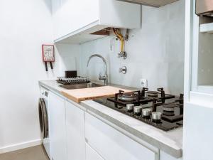 - une cuisine blanche avec cuisinière et évier dans l'établissement Condominio Serra Dani, à Nazaré