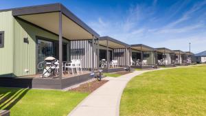 a row of houses with tables and chairs on a lawn at The Retreat West Beach Parks in Adelaide