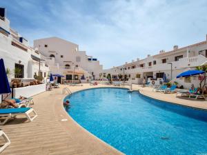a swimming pool in a resort with people laying on chairs at Port Royale 291, Spacious Studio in Los Cristianos