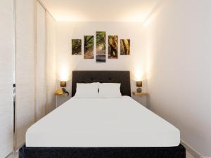 a bedroom with a white bed and paintings on the wall at Port Royale 291, Spacious Studio in Los Cristianos +13 photos