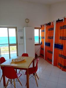 cocina con mesa, sillas y nevera en on the beach, en Gioiosa Marea