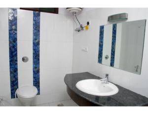 a bathroom with a sink and a toilet and a mirror at Hotel Jasmine, Haridwar in Haridwār