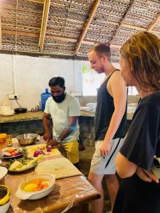 a group of people standing in a kitchen preparing food at Swiss kiss beach resort in Uppuveli