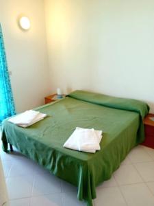 1 dormitorio con 1 cama verde y 2 almohadas blancas en on the beach, en Gioiosa Marea