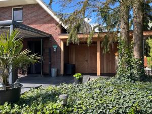 a brick house with a garage and a tree at Luxe Mediterraanse Suite in Rijssen