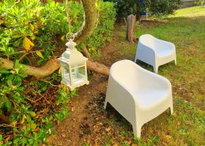 2 chaises blanches et une lanterne suspendue à un arbre dans l'établissement Residenza Gramsci, à Matera