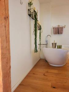 een badkamer met een wit bad op een houten vloer bij Wohnen am Dom in Geisenheim