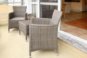 - 2 chaises en osier et une table sur une terrasse couverte dans l'établissement Residenz am Strand, Whg 238, à Zingst