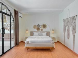 a white bedroom with a bed and a large window at Tujuan Jogja Villas With Private Pool in Jetis