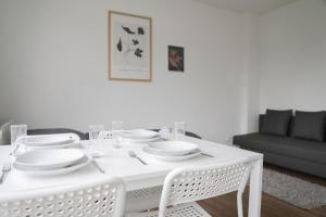 Biały stół jadalny z białymi daniami na nim w obiekcie Apartment in Schwerte w mieście Schwerte