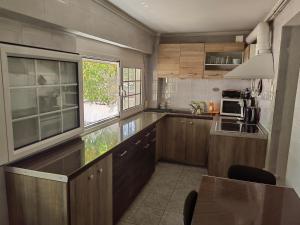 薩拉米斯的住宿－ILIAKTI RELAXING SEASIDE，厨房配有木制橱柜、桌子和窗户。