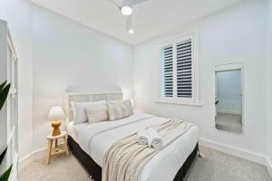 ein weißes Schlafzimmer mit einem Bett und einem Spiegel in der Unterkunft Phoenix at Palm View Collective in Sydney