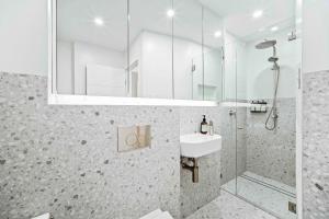 ein Bad mit einem Waschbecken, einer Dusche und einem Spiegel in der Unterkunft Phoenix at Palm View Collective in Sydney