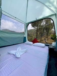 - un lit blanc dans une tente avec fenêtre dans l'établissement Whispering Pines Farmstay, à Lava