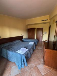 sypialnia z dwoma łóżkami i telewizorem w obiekcie La nuova locanda w mieście Orsomarso