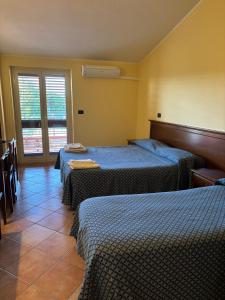 a hotel room with three beds and a window at La nuova locanda in Orsomarso