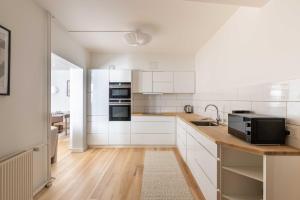 a kitchen with white cabinets and a sink and a microwave at Stylish Apartments in CPH City in Copenhagen