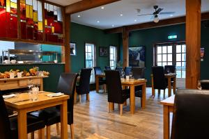 restauracja z drewnianymi stołami i krzesłami oraz zielonymi ścianami w obiekcie Lime Tree Hotel w mieście Fort William