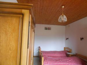 een slaapkamer met een bed met een rode sprei en een houten plafond bij bouton d or in La Bresse