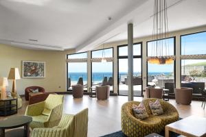 a living room with chairs and tables and windows at The Scarlet Hotel in Mawgan Porth