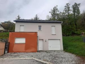 eine weiße Garage mit orangefarbener Tür in einer Einfahrt in der Unterkunft La Villa des Cimes in Pelleautier