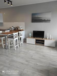 ein Wohnzimmer mit einem Tisch und einem TV sowie eine Küche in der Unterkunft Apartament Przy Latarni in Krynica Morska